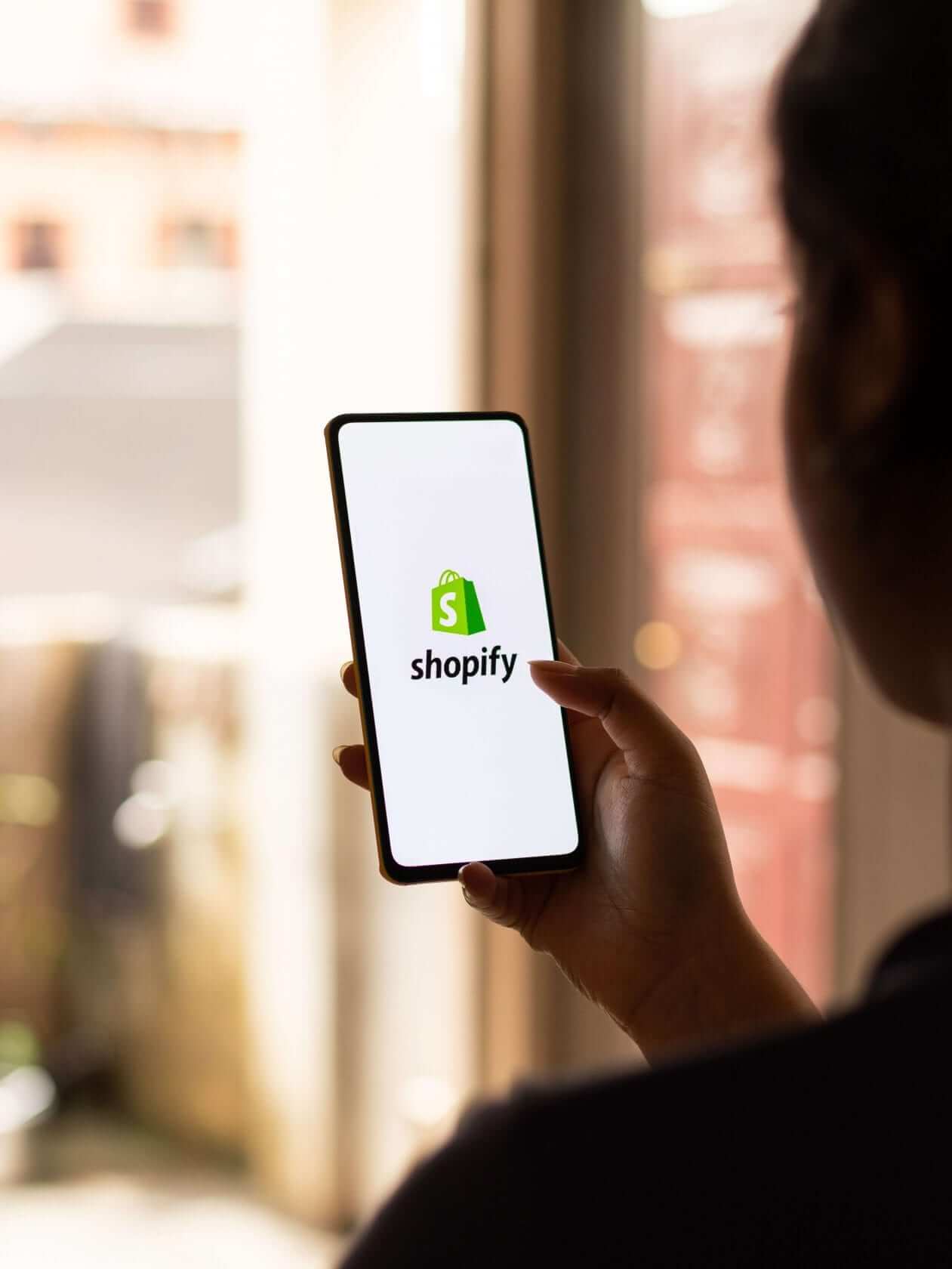 Smartphone mit Shopify-Logo auf dem Bildschirm für E-Commerce und ERP-Integration.