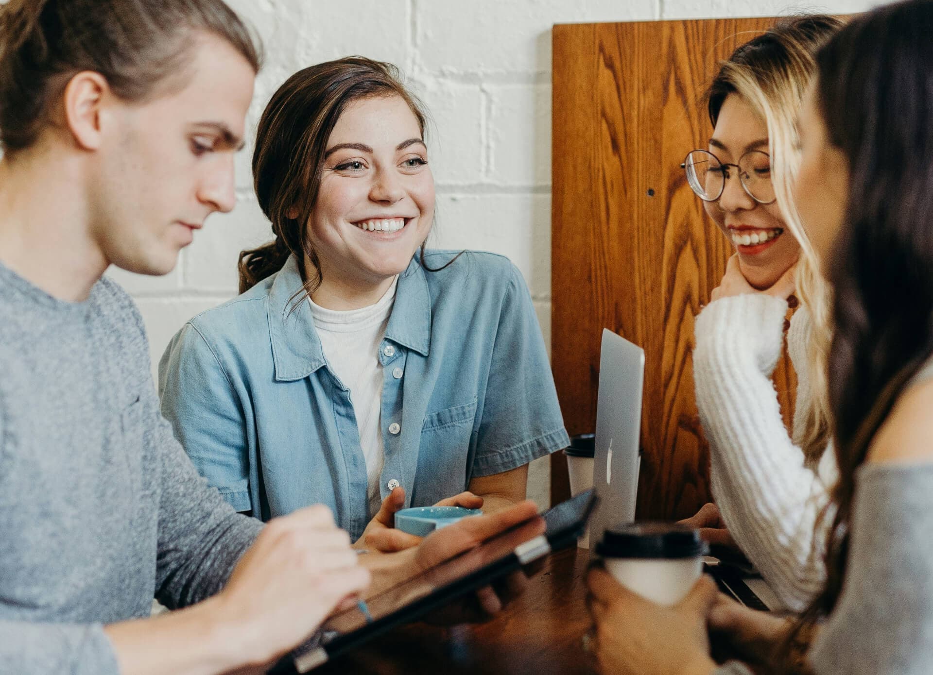 4 Personen sitzen eng zusammen an einem Tisch und unterhalten sich. Wir zeigen dir, wie du deine Zielgruppe effizient über verschiedene Kanäle im Multichannel-Marketing ansprichst!