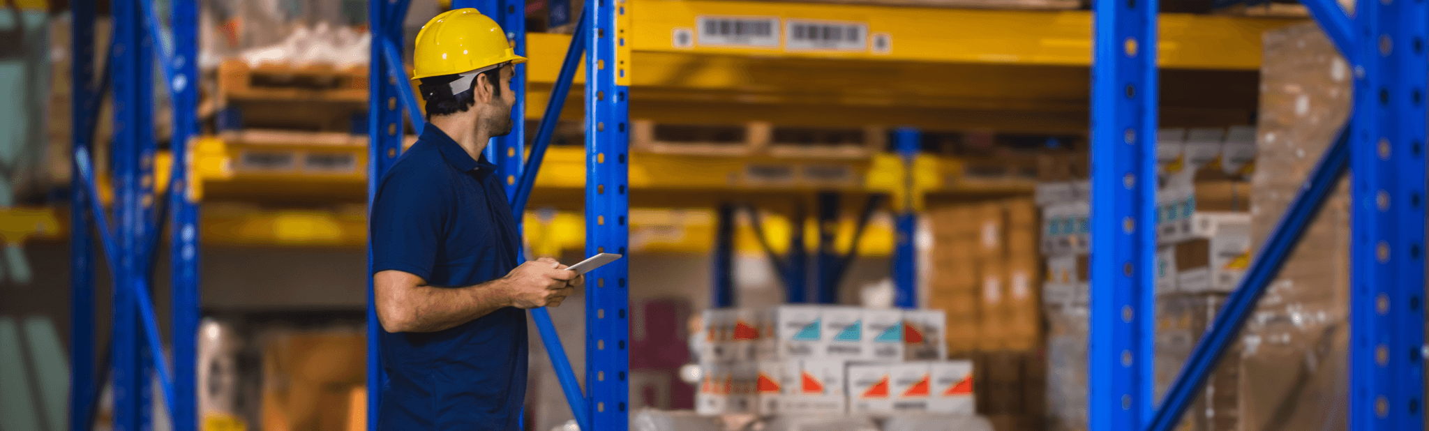 Lagerarbeiter mit Tablet in der Hand zwischen Regalen