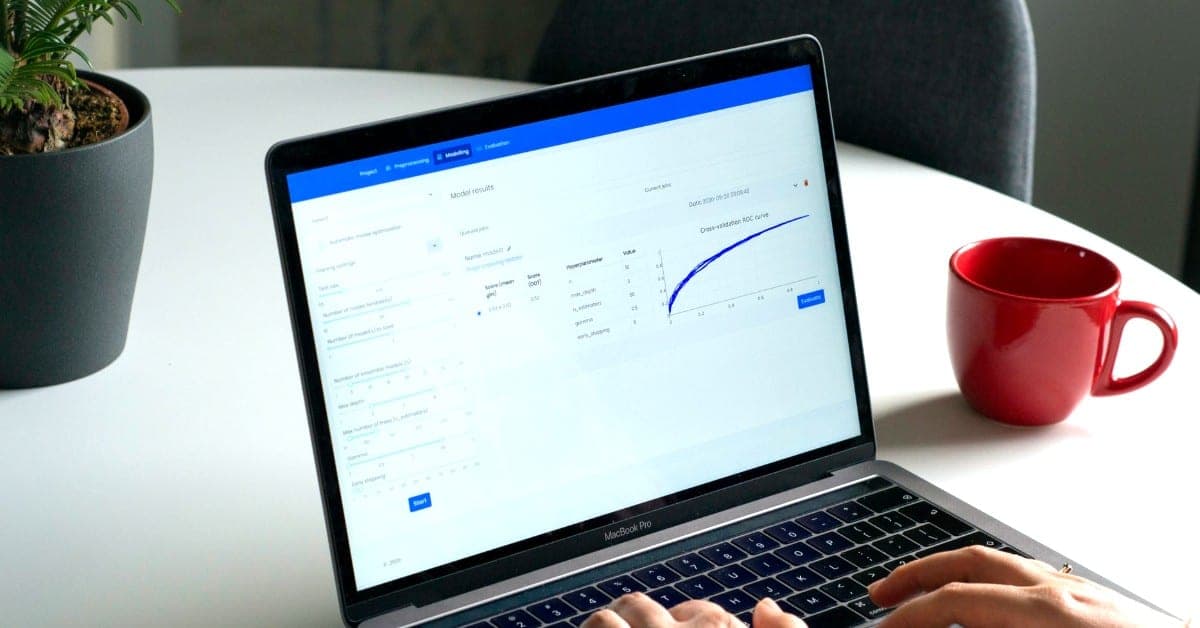 View of an opened laptop standing on a white table in front of a houseplant and next to a red coffee cup. A person is looking at a dashboard and typing something on the keyboard. Keeping track of a multichannel system is hard. We'll show you what's important!